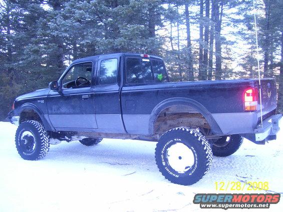 Dark blue and grey Ford Ranger pickup truck with lifted suspension and off-road tires in snow