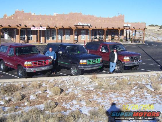 Three 1993 Ford Broncos parked in a lot. Two men stand by the vehicles