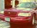 1999 Ford Crown Victoria - A red Ford Crown Victoria is parked in front of a garage with snow on the ground.