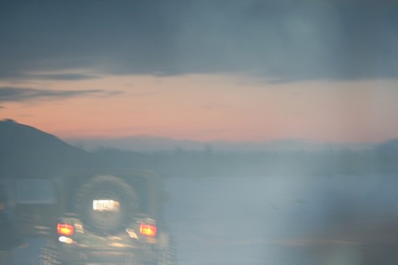 Jeep Wrangler rear view with spare tire and taillights on, sunset sky