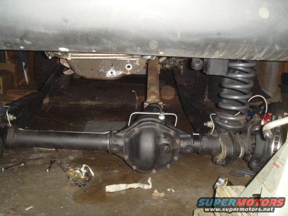 Rear axle assembly with differential housing and driveshaft, viewed from underneath a vehicle