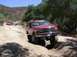 1996 Ford Bronco - 1996 Ford Bronco navigating an off-road trail with another vehicle in the background.