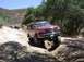 1996 Ford Bronco - This red SUV is tackling a challenging off-road path, with another vehicle following behind.