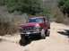 1996 Ford Bronco - This red Ford F-Series pickup truck, likely from the early to mid-1990s, navigates a dusty, off-road trail.