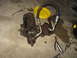 1978 Ford Bronco - A used steering gear box with attached hydraulic lines rests on a stained concrete surface next to tools.