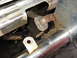 1978 Ford Bronco - Detail of a corroded bracket and exhaust pipe, likely from an older vehicle.
