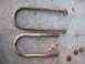 1978 Ford Bronco - Two rusty U-bolts and nuts are shown on a concrete surface.