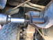 1978 Ford Bronco - A socket wrench is used to adjust a bolt on the suspension system of a vehicle, with a tire in view.