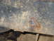 1978 Ford Bronco - Close-up view of a heavily rusted metal frame section, showing wear and tear.