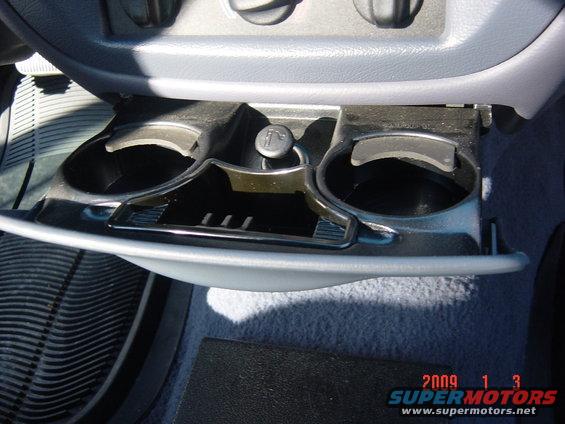 Center console with two cup holders, an open ashtray, and a cigarette lighter, showing a timestamp of 2009