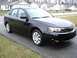 2008 Subaru Impreza - A black sedan is parked on a wet driveway in front of a row of houses.