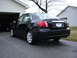 2008 Subaru Impreza - A black 2008 Subaru Impreza sedan is parked in front of a garage.