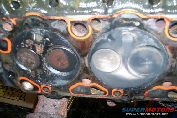 Engine cylinder head showing two valves, one with carbon buildup