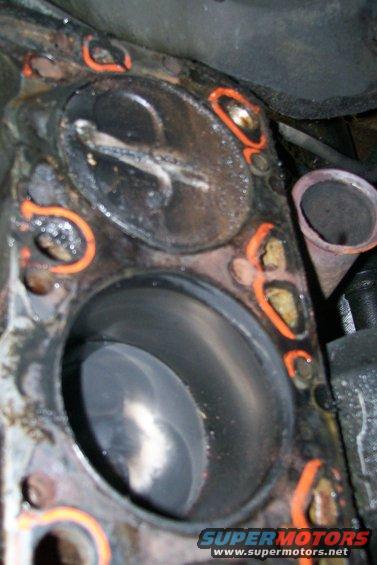 Engine cylinder with damaged head gasket. Orange sealant is visible around the cylinder bore