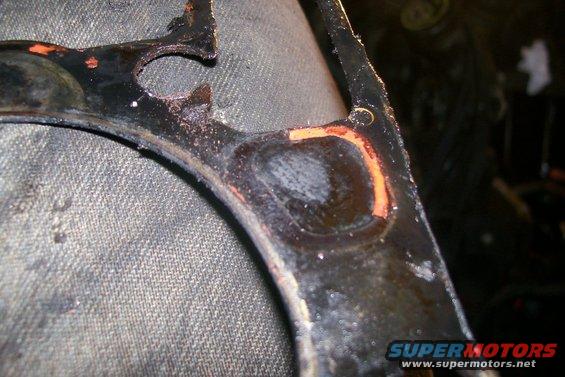close-up of a damaged engine gasket with orange sealant visible