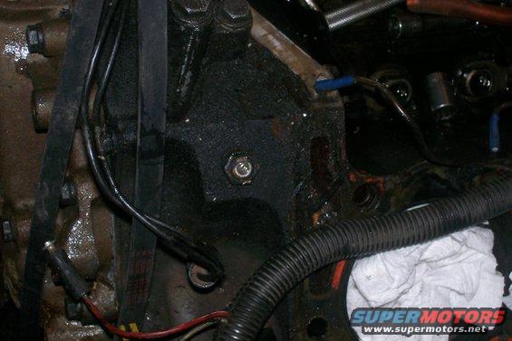 Engine block with oil residue, black hoses, and wiring. A white cloth is visible