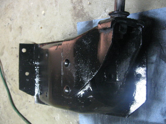 black painted metal bracket with bolts, sitting on a blue cloth on concrete