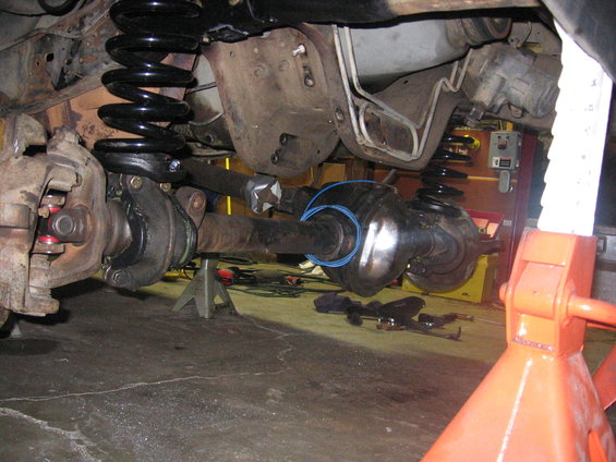 Undercarriage view showing vehicle suspension and axle components, including a differential housing and driveshaft