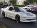 1994 Ford Probe - A white 1994 Ford Probe is parked outside a building, showing its custom hood and body kit.