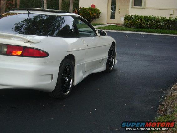 White coupe with black rims and a spoiler, viewed from the rear three-quarter angle