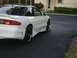 1994 Ford Probe - A white coupe with aftermarket wheels and a body kit is parked on a dark asphalt driveway.
