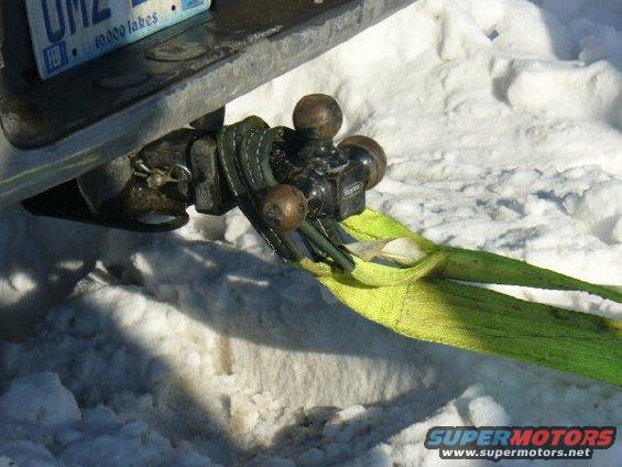 Tow hitch with dual balls and a yellow tow strap attached, resting on snow