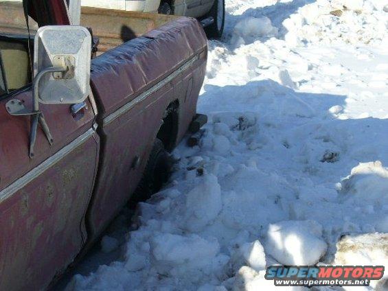 Side view of a red 1978 Ford F-150 stuck in deep snow