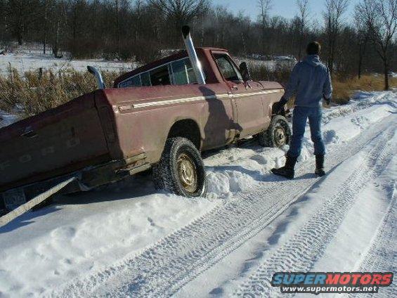 Side view of a maroon 1978 Ford F-150 stuck in snow with dual exhaust pipes