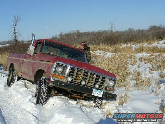 Red 1978 Ford F-150 stuck in snow, driver visible in cab