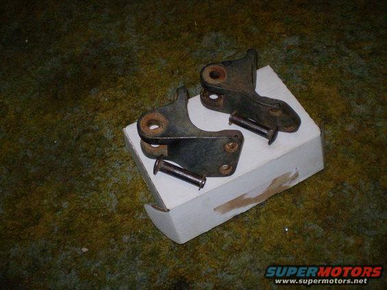 Two rusty metal brackets and pins resting on a white box