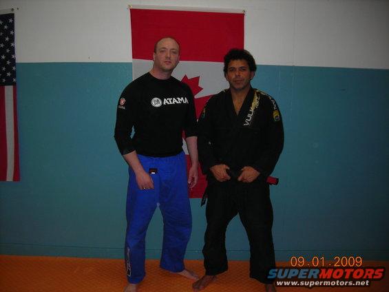 Two men stand in front of Canadian and American flags