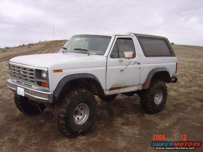 White Ford Bronco with aftermarket wheels and tires parked on a dirt hill