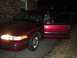 1994 Ford Crown Victoria - A red sedan is parked outside a brick building at night with its driver's door ajar.