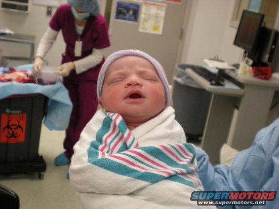 Newborn baby wrapped in a striped blanket in a hospital room