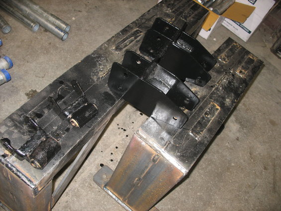 Painted black metal suspension brackets and some metal pipes on a workbench