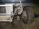 1995 Ford C-350 (Centurion Conversions) - Close-up view of the front suspension components and radiator of a vehicle, with a chain attached to the frame.