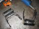 1995 Ford C-350 (Centurion Conversions) - Two black metal suspension parts with rubber bushings are shown on a metal surface next to a tape measure and air tool.