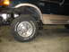 1995 Ford C-350 (Centurion Conversions) - The front wheel and side of a 1995 Ford C-350 (Centurion Conversions) van are visible, showing its two-tone paint scheme.