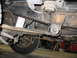 1995 Ford C-350 (Centurion Conversions) - A close-up view of the undercarriage reveals the vehicle's suspension components and a white oil filter.