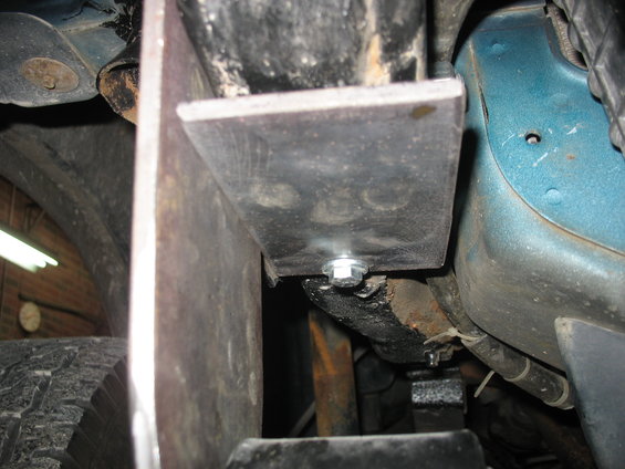 Close-up of a custom metal bracket bolted to a vehicle's frame near the tire