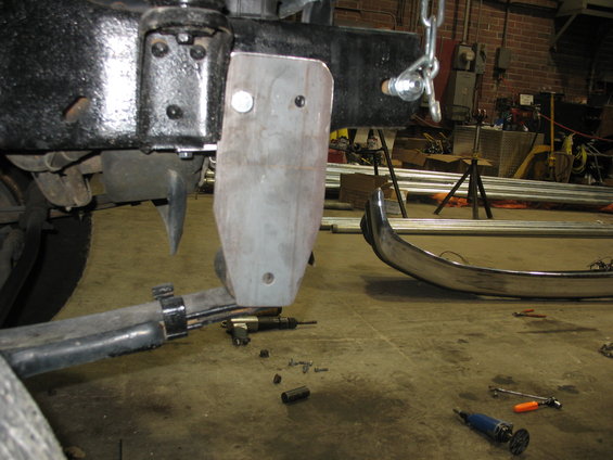 Close-up of a vehicle's black frame with a metal plate attached to the suspension