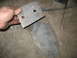 1995 Ford C-350 (Centurion Conversions) - Two metal bracket components, likely for a vehicle suspension system, are shown with a hand holding one piece.