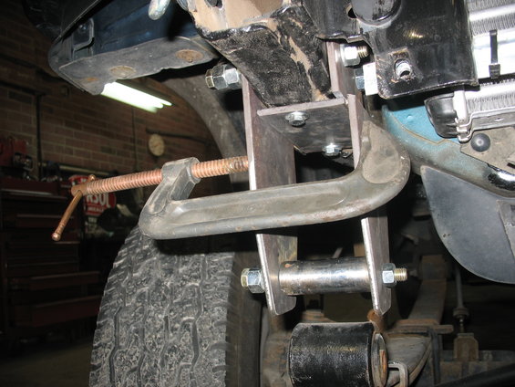 Close-up of a C-clamp on a vehicle's suspension part, showing metal brackets and bolts