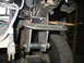 1995 Ford C-350 (Centurion Conversions) - A custom suspension component is being worked on, secured with a clamp.
