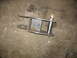 1995 Ford C-350 (Centurion Conversions) - A fabricated metal part, likely for a vehicle's suspension system, rests on a rough concrete surface.