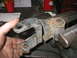 1995 Ford C-350 (Centurion Conversions) - A heavily rusted metal suspension component is clamped in a vise, showing signs of wear and damage.