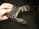 1995 Ford C-350 (Centurion Conversions) - A rusty metal suspension part, likely from a vehicle, is held by a hand.