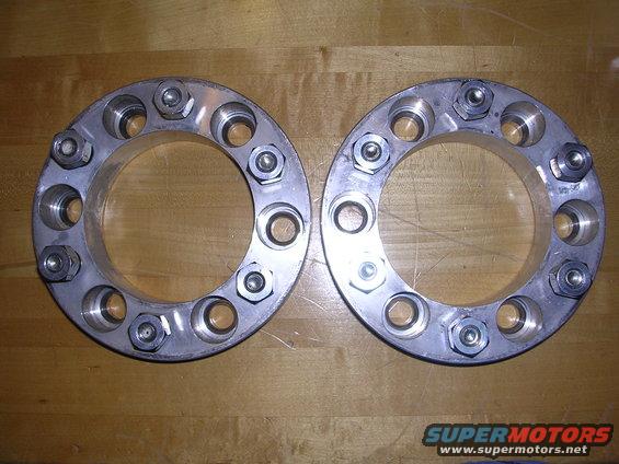 Two brake rotors with drilled holes and markings on a wooden surface