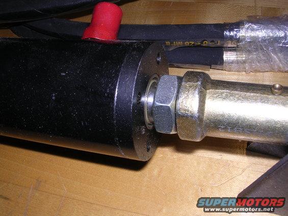 Close-up of a hydraulic cylinder with a red cap on a hose and a brass fitting