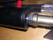 1983 Ferrari Enzo - Hydraulic cylinder part with hose and fittings visible, on a wooden surface.